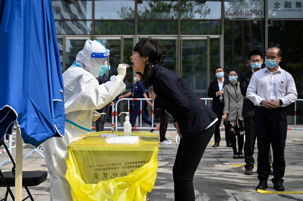 A health worker takes a swab sample from a woman at a Covid-19 coronavirus testing site outside office buildings in Beijing on April 29, 2022. Photo: AFP