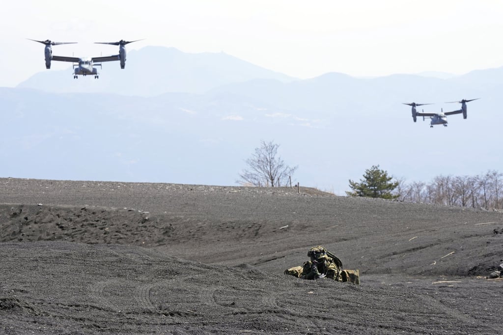 Two MV-22 Ospreys fly over as one of the members of the Japan Ground Self-Defence Force (JGSDF) guards a landing zone during a joint military drill with the US Marines in March. AP: Photo