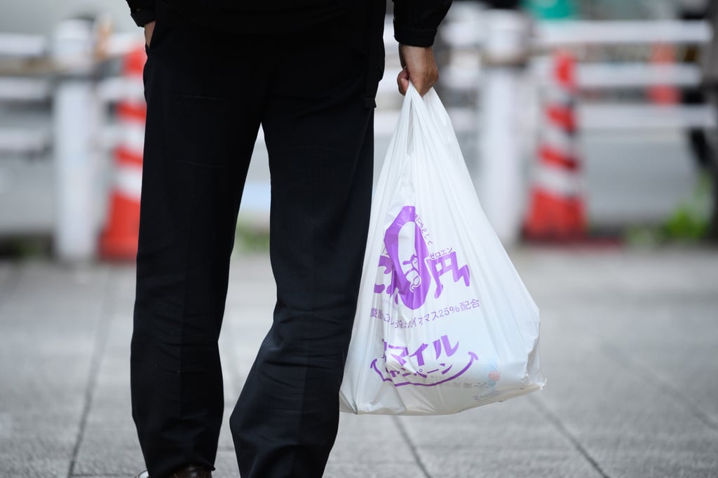 A customer carries a plastic bag from a discount store in Tokyo last month. Japanese consumers are tightening their belts as inflation looms. Photo: Bloomberg