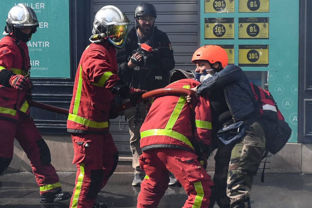 A protester attempts to stop firefighters from putting out a fire amid clashes on the sidelines of the annual May Day rally in Paris, France on May 1. Photo: AFP