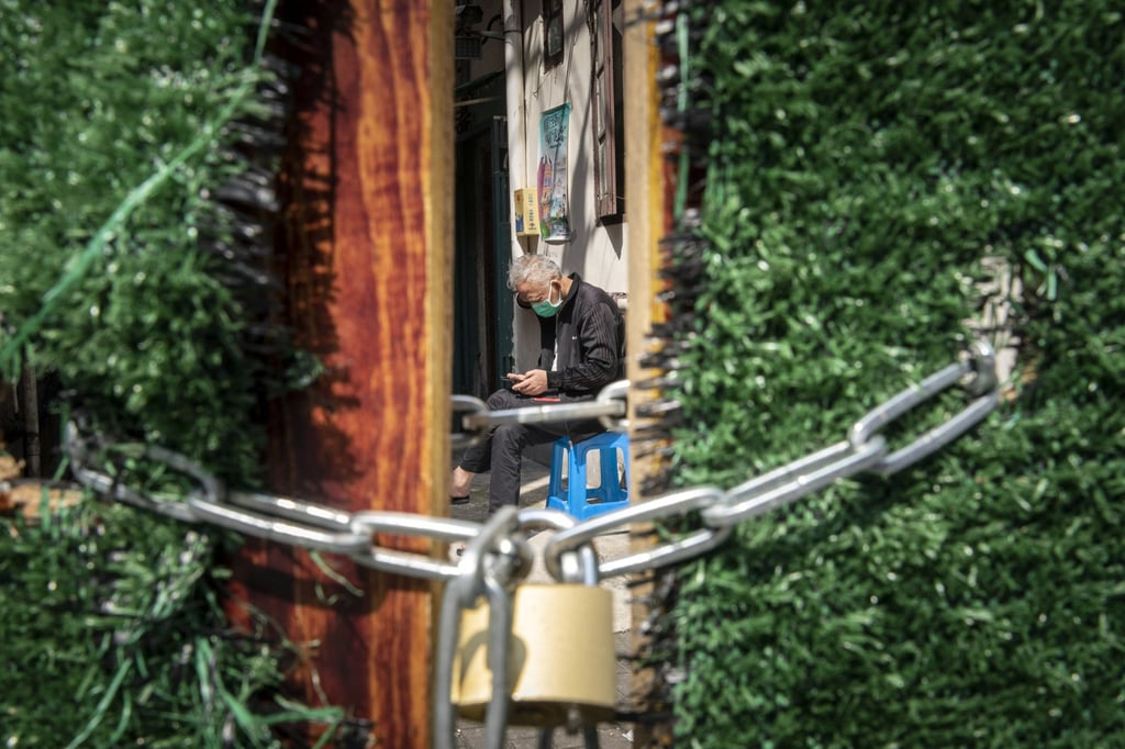 A resident sits behind a locked gate at a neighbourhood in Shanghai on May 3, 2022. Photo: Bloomberg