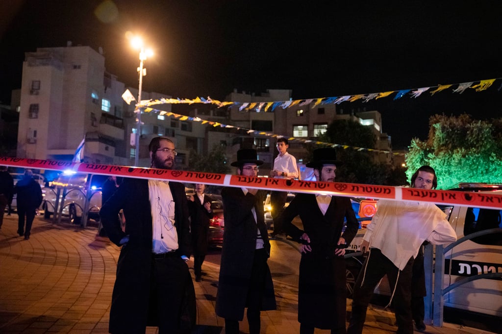 Ultra-Orthodox Jews stand behind police tape after a fatal attack in Elad, Israel. Photo: AP