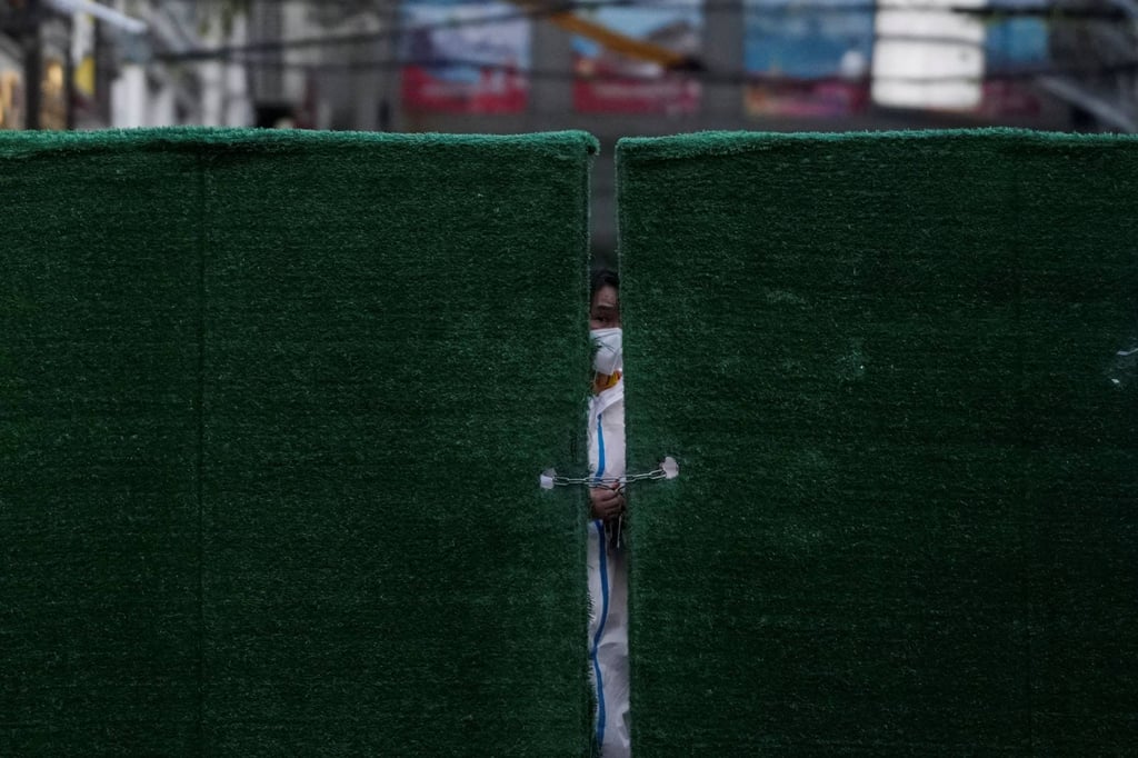 A worker in a protective suit locks a barrier of a residential area amid the lockdown in Shanghai, on May 4, 2022. Photo: Reuters