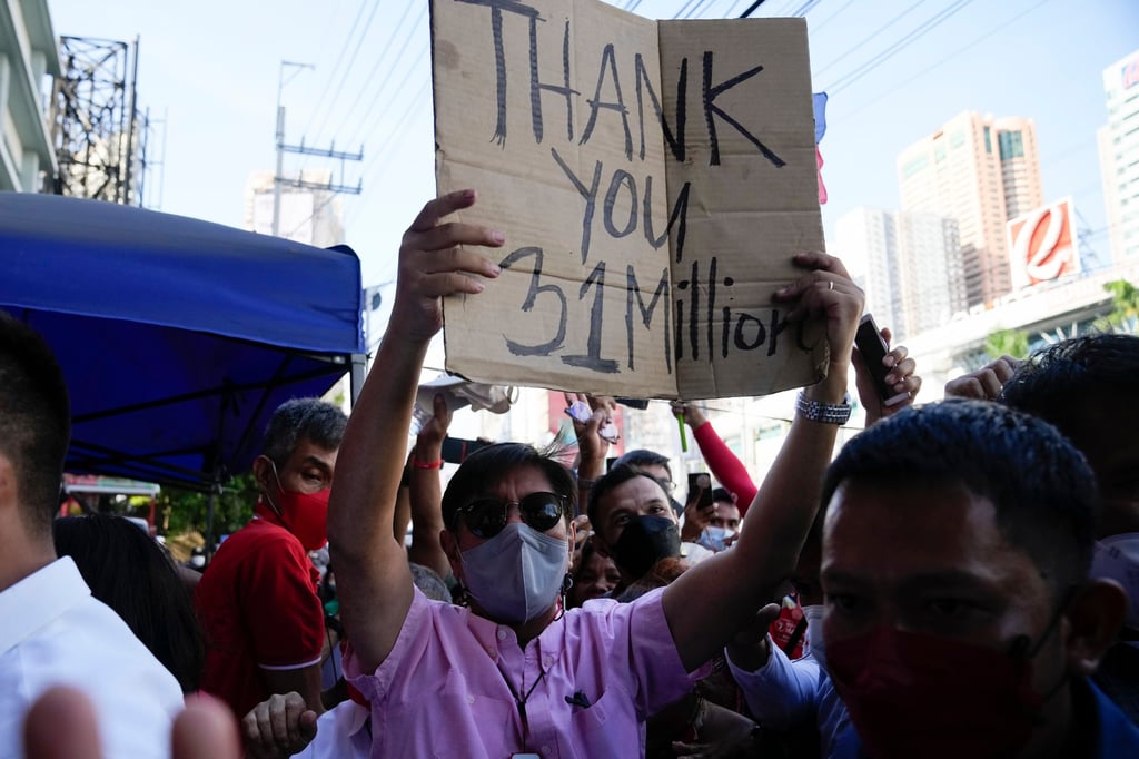 Presidential candidate Ferdinand “Bongbong” Marcos Jnr holds a sign he got from the crowd as he celebrates outside his headquarters in Mandaluyong, Philippines. Photo: AP