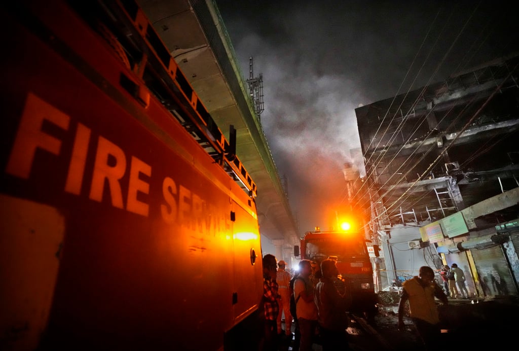 Fire officials try to douse a fire in a four storey building, in New Delhi, India. Dozens were killed in the blaze. Photo: AP