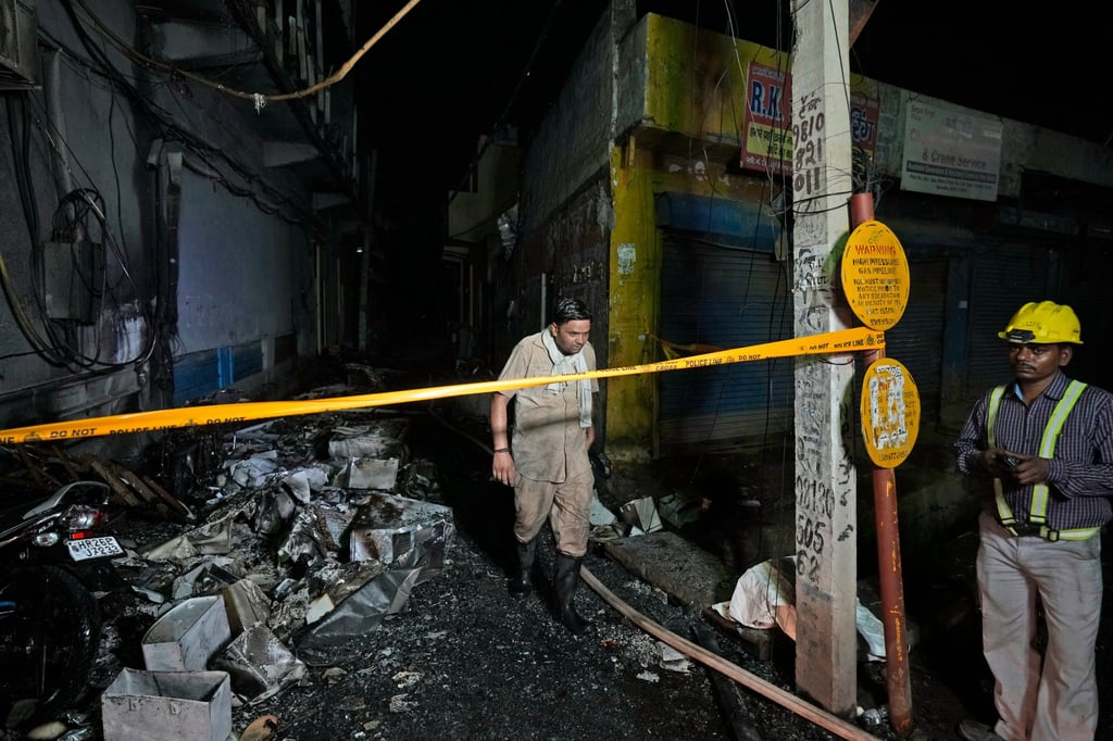 A fire official returns after controlling a fire in a four storey building, in New Delhi. Photo: AP
