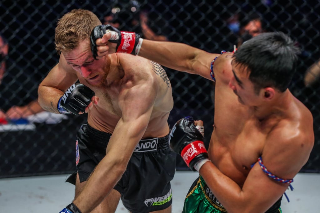 Petchmorakot (right) lands a right hook on Jimmy Vienot in a featherweight Muay Thai title fight at ONE 157 in Singapore.