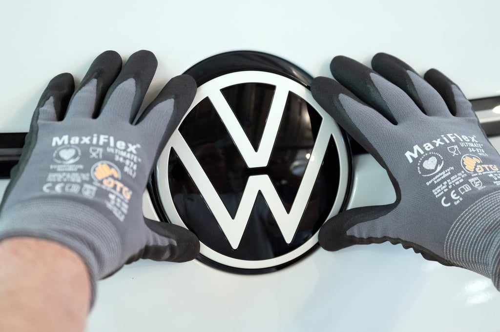 A Volkswagen employee places the VW logo in a VW ID.3. Photo: DPA