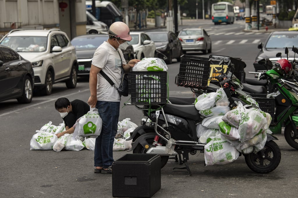 Delivery workers sort through produce orders outside a Meituan fresh food delivery station in Shanghai on Friday. Photo: Bloomberg