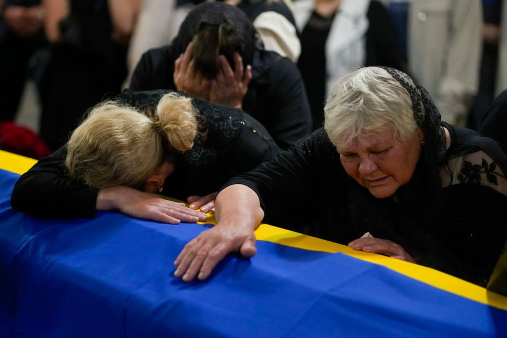 Ukrainian Army Colonel Oleksander Makhachek’s mother, right, and sister mourn over his coffin at his funeral on Friday. Photo: AP