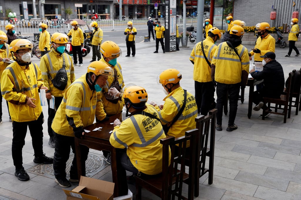 Meituan delivery workers hold antigen testing kits as they line up to get tested for the coronavirus in Beijing, China on May 9. Photo: Reuters
