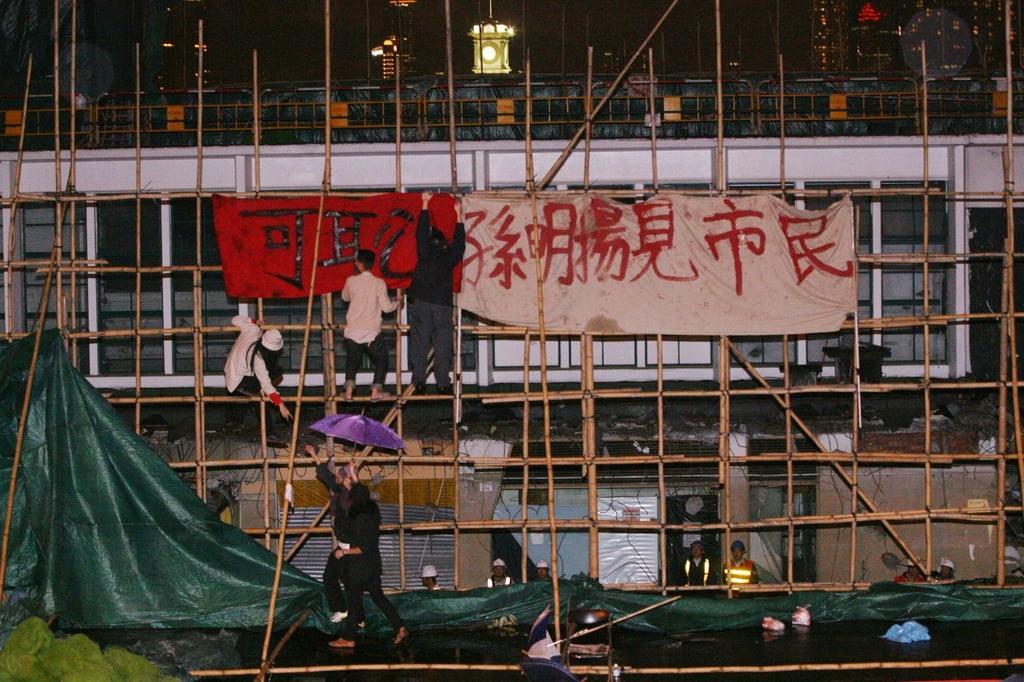 People protesting against the demolition of the Star Ferry pier in Central, Hong Kong, hang banners outside the construction site. Photo: David Wong