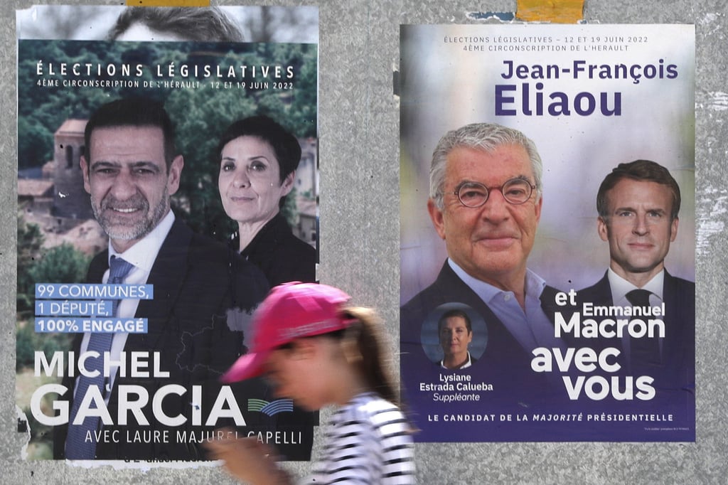 A woman walks past legislative election posters in Gignac, France earlier this month. Photo: EPA-EFE