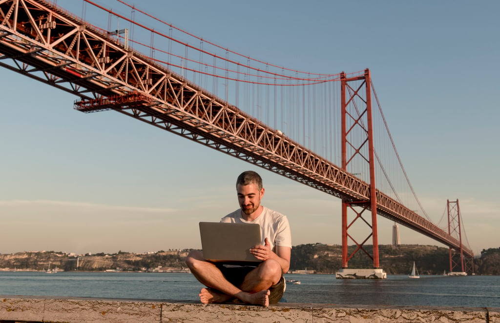 A man works on a laptop under a bridge in Lisbon, Portugal. Photo: Getty Images A man works on a laptop under a bridge in Lisbon, Portugal. Photo: Getty Images