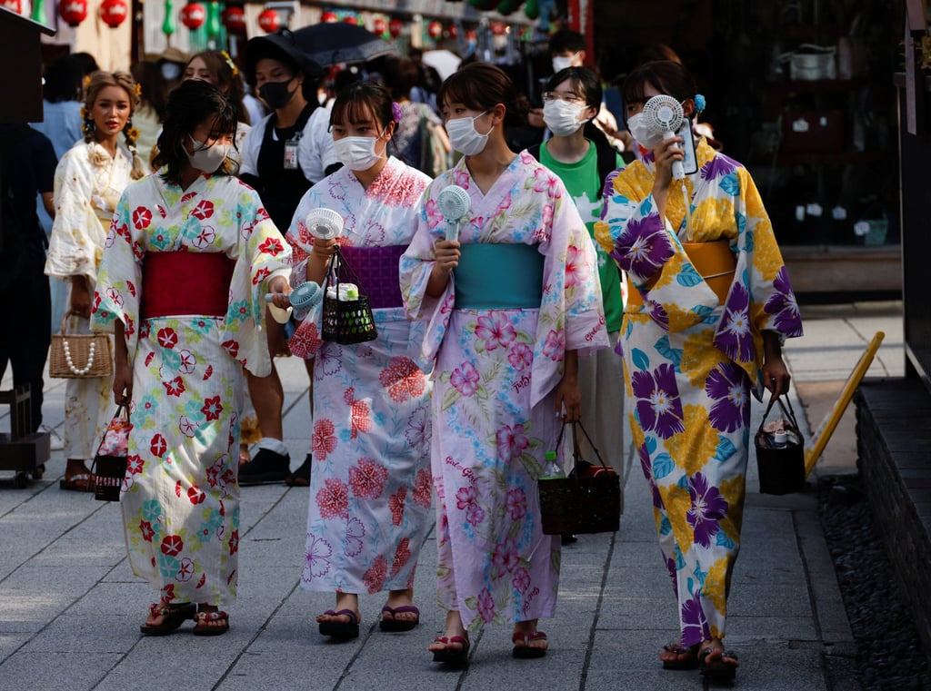 Women wearing summer kimonos use portable fans as they walk on the street in Tokyo last month. Photo: Reuters