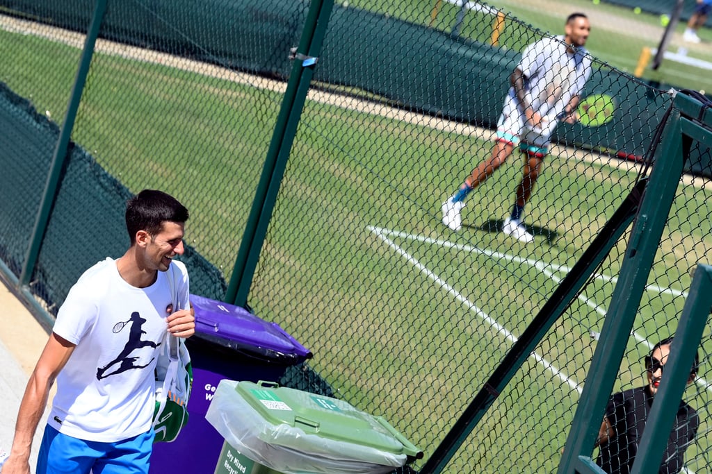 Australia’s Nick Kyrgios during training as Serbia’s Novak Djokovic walks past after his training. Photo: Reuters