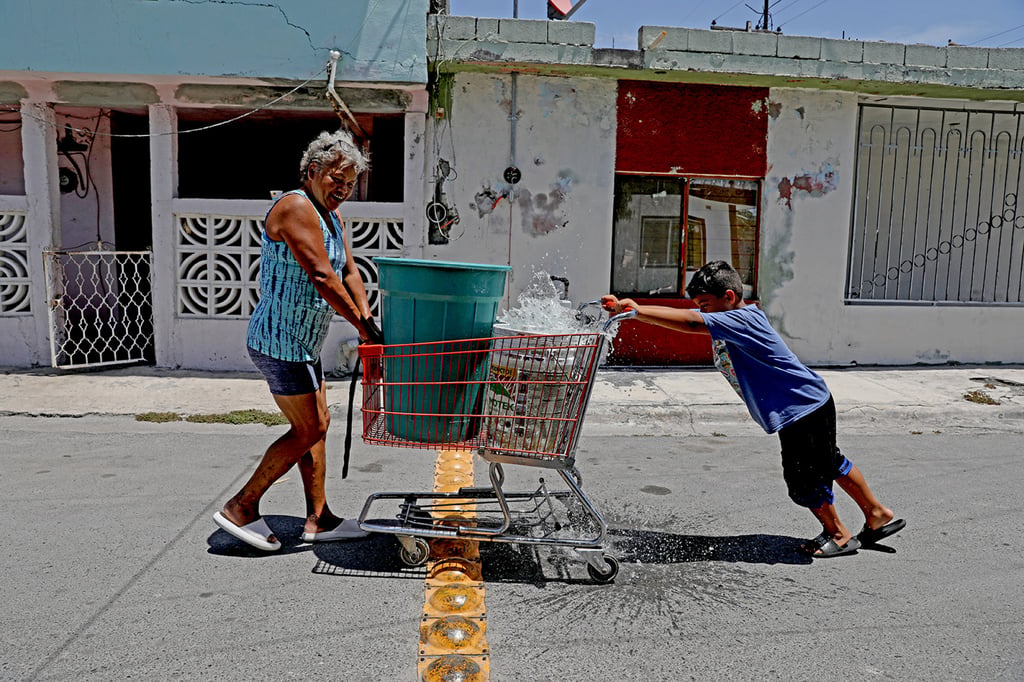 A woman and her grandson push a shopping trolley filled with containers of water delivered by a tanker truck on the outskirts of Monterrey, Mexico. Photo: TNS