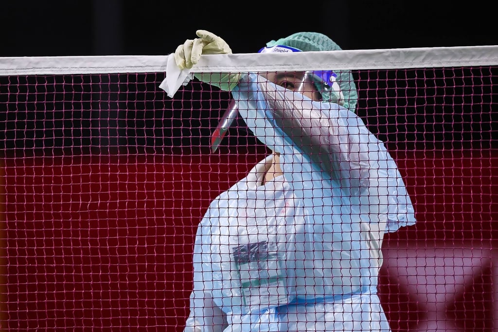 An official wearing a face mask and shield cleans the net as a preventive measure against the spread of Covid-19 at the 2021Thailand Open in Bangkok. Photo: AFP