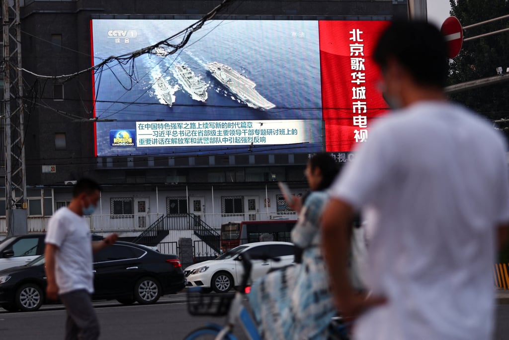 People walk past a screen showing footage of Chinese navy ships during an evening news programme in Beijing on Tuesday. Photo: Reuters People walk past a screen showing footage of Chinese navy ships during an evening news programme in Beijing on Tuesday. Photo: Reuters