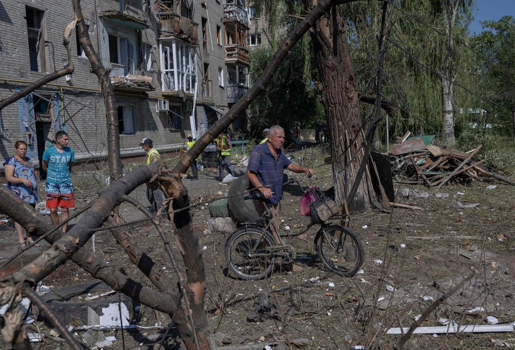 A man pushes his bicycle past a destroyed building in Sloviansk on July 29. Photo: AFP