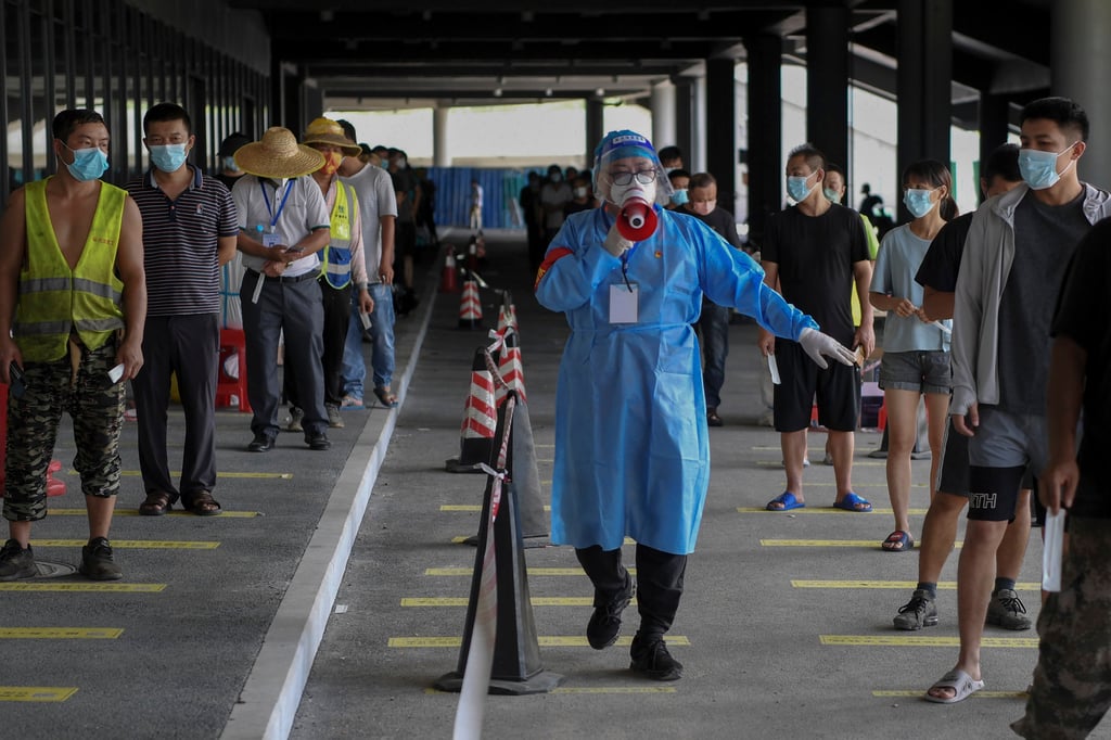 A volunteer urges people to maintain social distancing at a Covid-19 testing site in Sanya. Photo: Xinhua via AP A volunteer urges people to maintain social distancing at a Covid-19 testing site in Sanya. Photo: Xinhua via AP