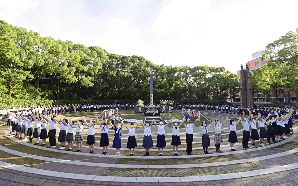 High-school students form a ring around the hypocentre cenotaph in Nagasaki on Tuesday during a ceremony marking the 77th anniversary of the atomic bombing of the city. Photo: Kyodo