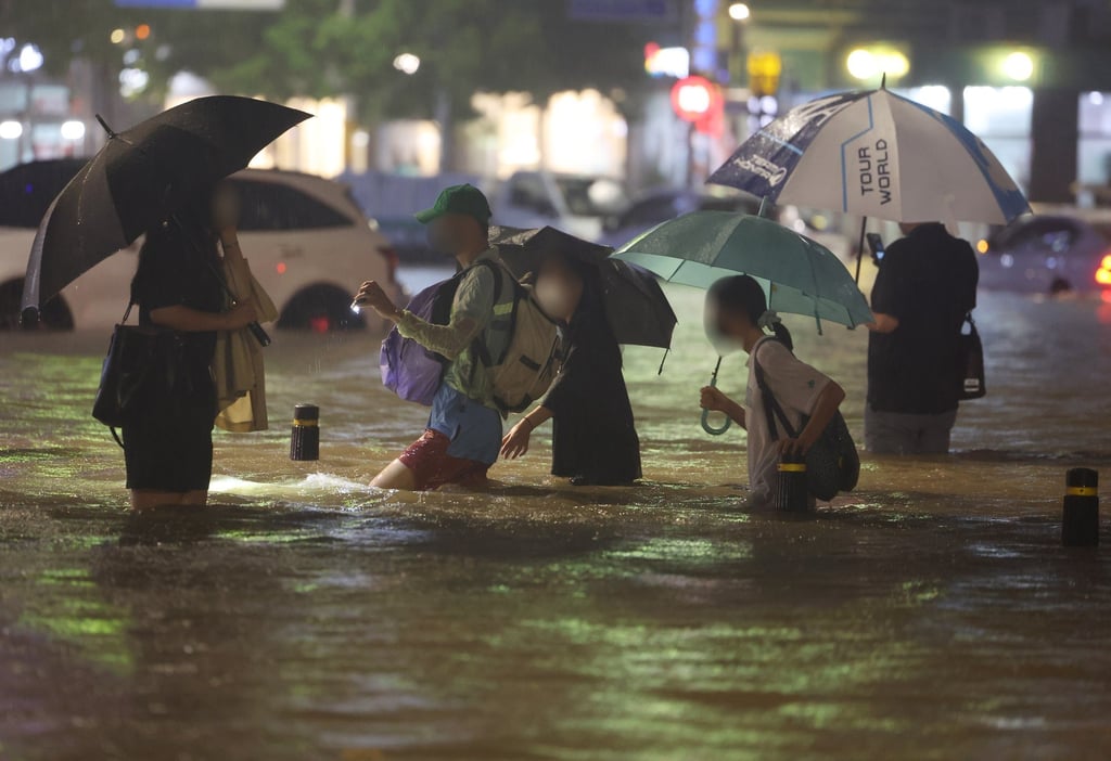 People wade though an inundated road in southern Seoul, South Korea, on Monday night amid some of the heaviest rainfall in 80 years. Photo: Yonhap/EPA-EFE