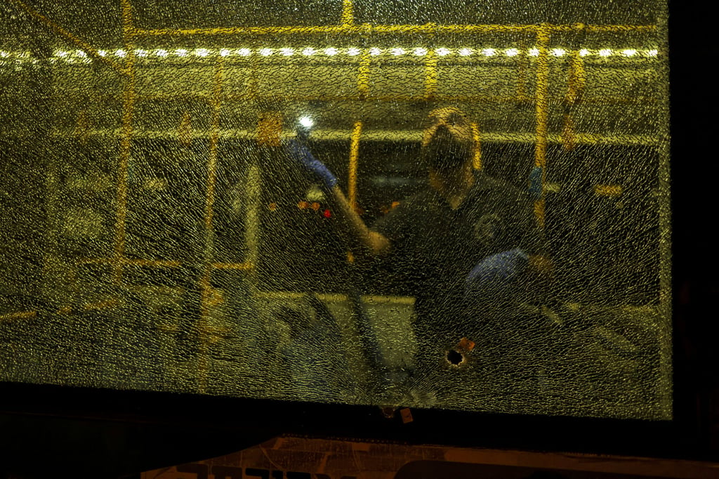 An Israeli security personal stands behind a shattered window of a bus as he checks it following an incident in Jerusalem on Sunday. Photo: Reuters