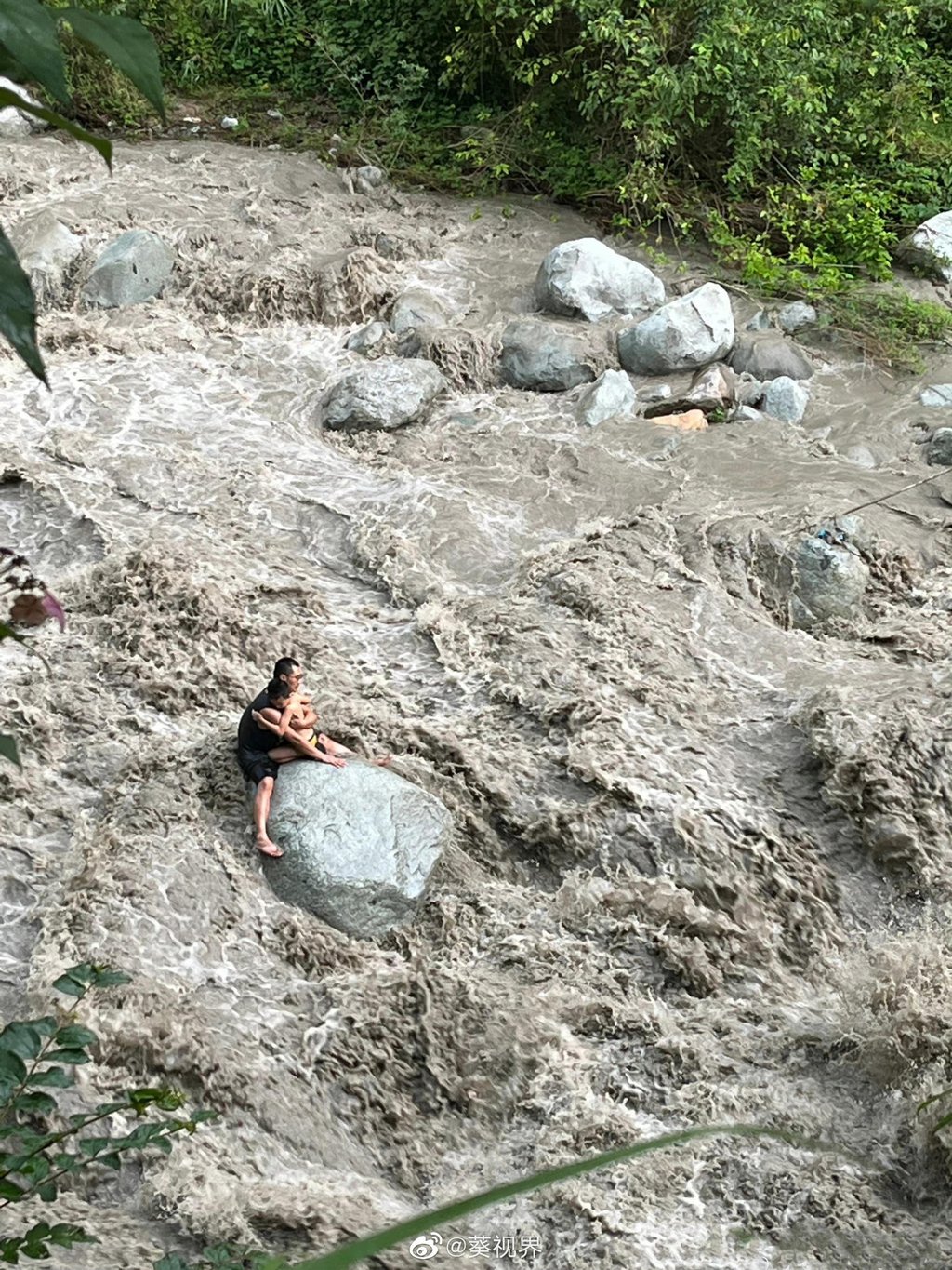 A boulder offers defence against the raging waters. Photo: Weibo