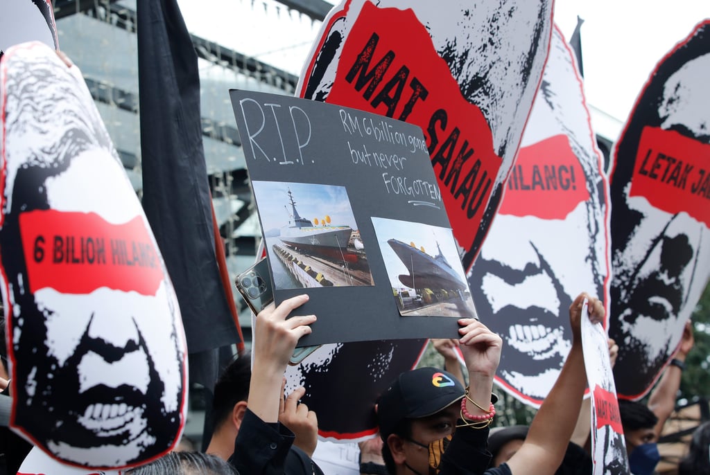 Protesters hold placards during a demonstration outside a shopping complex demanding the government form a royal commission of inquiry on the controversial littoral combat ship project. Photo: dpa