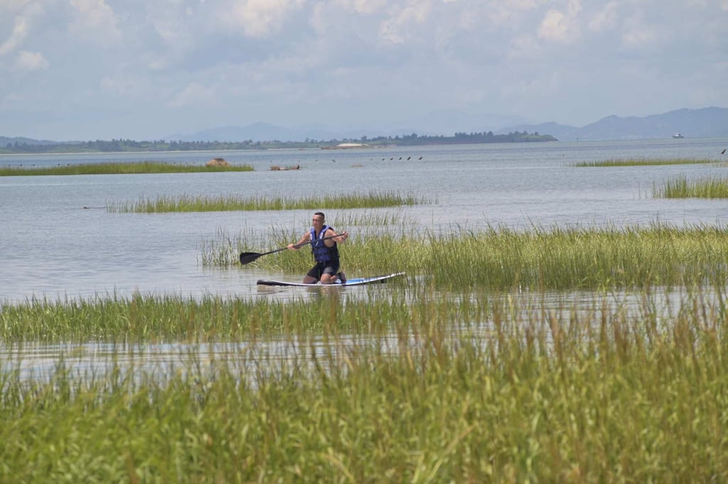 Joseph Lin paddles in waters off Quemoy, with the mainland Chinese city of Xiamen in the background. Photo: AFP