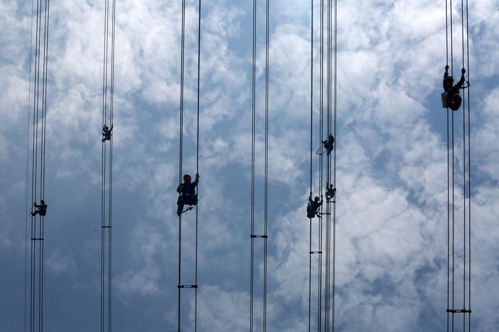 Workers of grid operator China Southern Power Grid inspect power cables connecting transmission towers in Dongguan in Guangdong province on May 29, 2018. Photo: Reuters