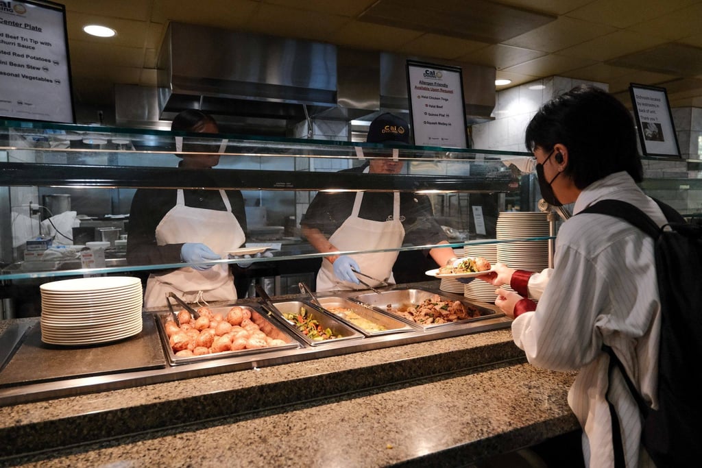 An employee hands a plate of food to a student at the dining hall on the University of California, Berkeley, campus in on August 30. College students returning to campus this fall will find their dining halls experimenting with everything from fewer salad dressings to “plant-powered” Mondays as schools look for ways to adapt to soaring inflation. Photo: Bloomberg An employee hands a plate of food to a student at the dining hall on the University of California, Berkeley, campus in on August 30. College students returning to campus this fall will find their dining halls experimenting with everything from fewer salad dressings to “plant-powered” Mondays as schools look for ways to adapt to soaring inflation. Photo: Bloomberg