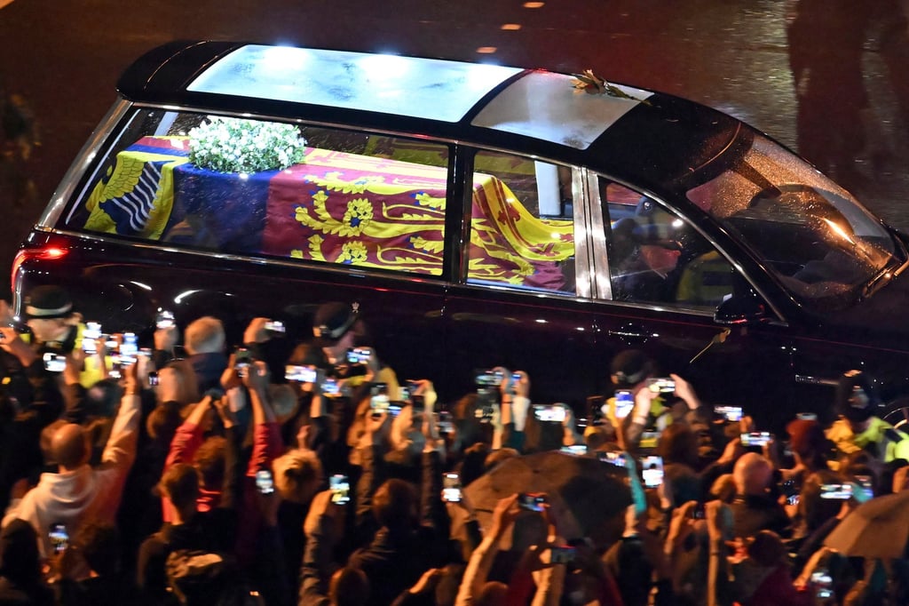 People line the streets in London to watch and photograph the coffin of Queen Elizabeth in the royal hears as it travels to Buckingham Palace on Tuesday. Photo: AP