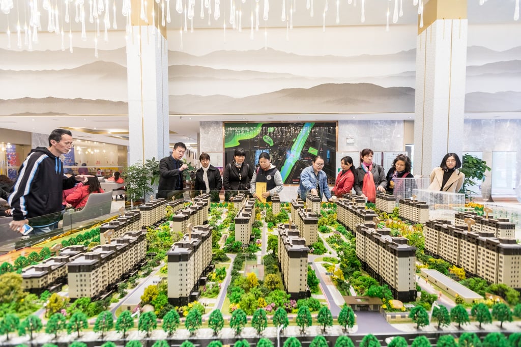 People inspect a replica model of apartments for sale in China. Photo: Shutterstock