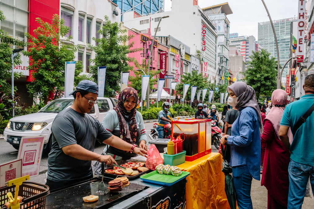 Food vendors serve a customer at a market in Kuala Lumpur. File photo: Bloomberg