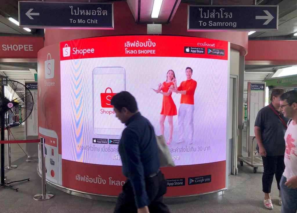 Commuters walk past an advertisement for online commerce site Shopee at a Bangkok skytrain station. Photo: Chua Kong Ho
