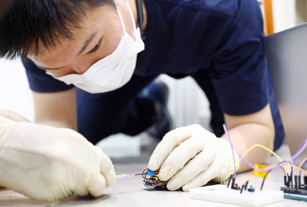 Researcher Yujiro Kakei connects a solar cell to a “backpack” of electronics mounted on a Madagascar hissing cockroach at the Thin-Film Device Laboratory of Japanese research institution Riken in Wako, Saitama Prefecture, Japan on September 16. Photo: Reuters Researcher Yujiro Kakei connects a solar cell to a “backpack” of electronics mounted on a Madagascar hissing cockroach at the Thin-Film Device Laboratory of Japanese research institution Riken in Wako, Saitama Prefecture, Japan on September 16. Photo: Reuters