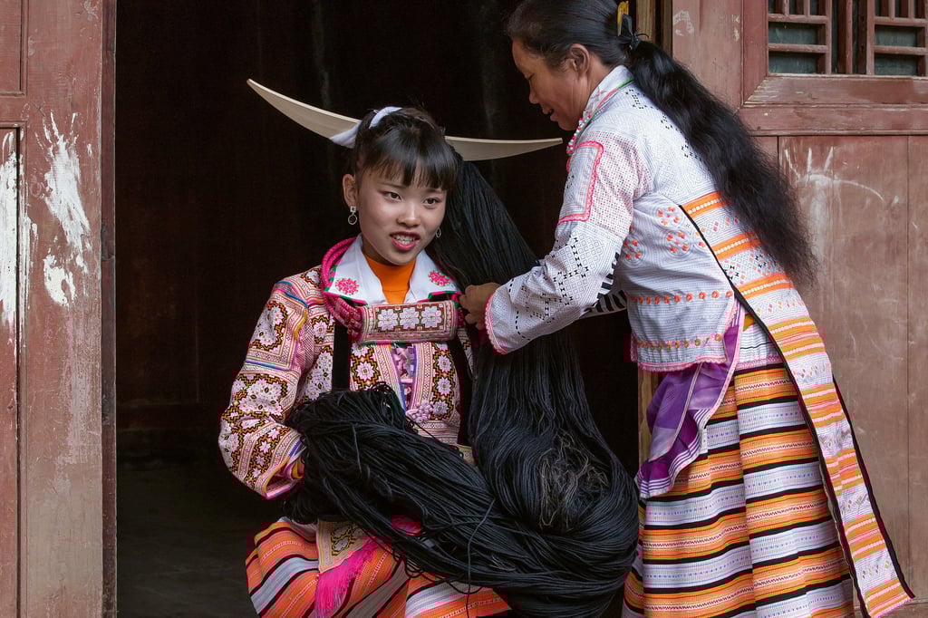 In preparation for a festival, a young Long Horn Miao woman dons an elaborate headpiece comprising a mix of wool and “ancestral hair”, some of which has been passed down through generations. Photo: Cat Vinton / Thames & Hudson
