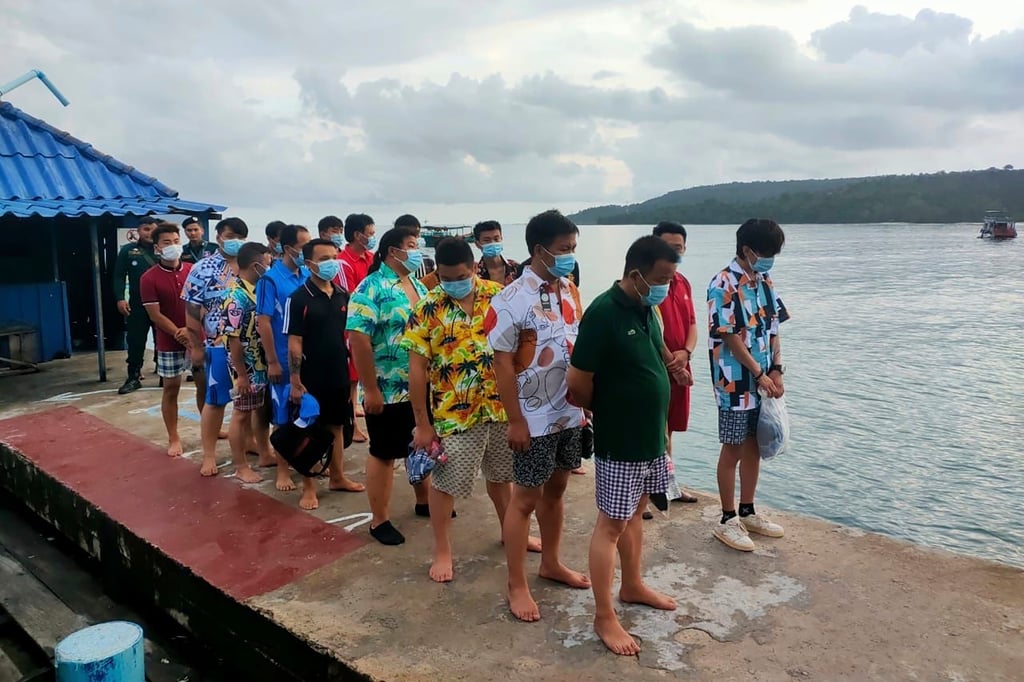 Chinese nationals stand on a pier after being rescued from a ship sinking, at an island in Preah Sihanouk Province, southwestern Cambodia on Thursday. Photo: Preah Sihanouk province authority police via AP