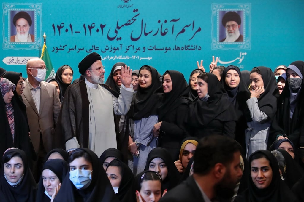 Iran’s President Ebrahim Raisi (centre) poses with female students for a picture during a ceremony marking the beginning of the academic year. In a poem he recited, he equated “rioters” to flies. Photo: EPA-EFE