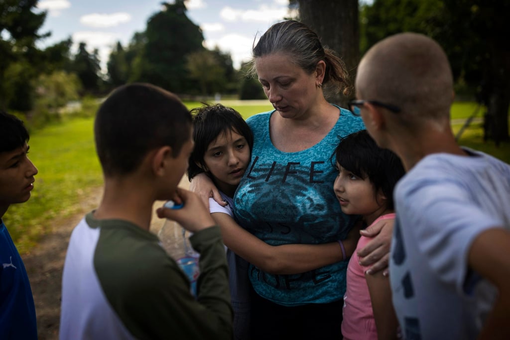 Olga Lopatkina embraces her adopted children in a park in Loue, western France, in July. Photo: AP