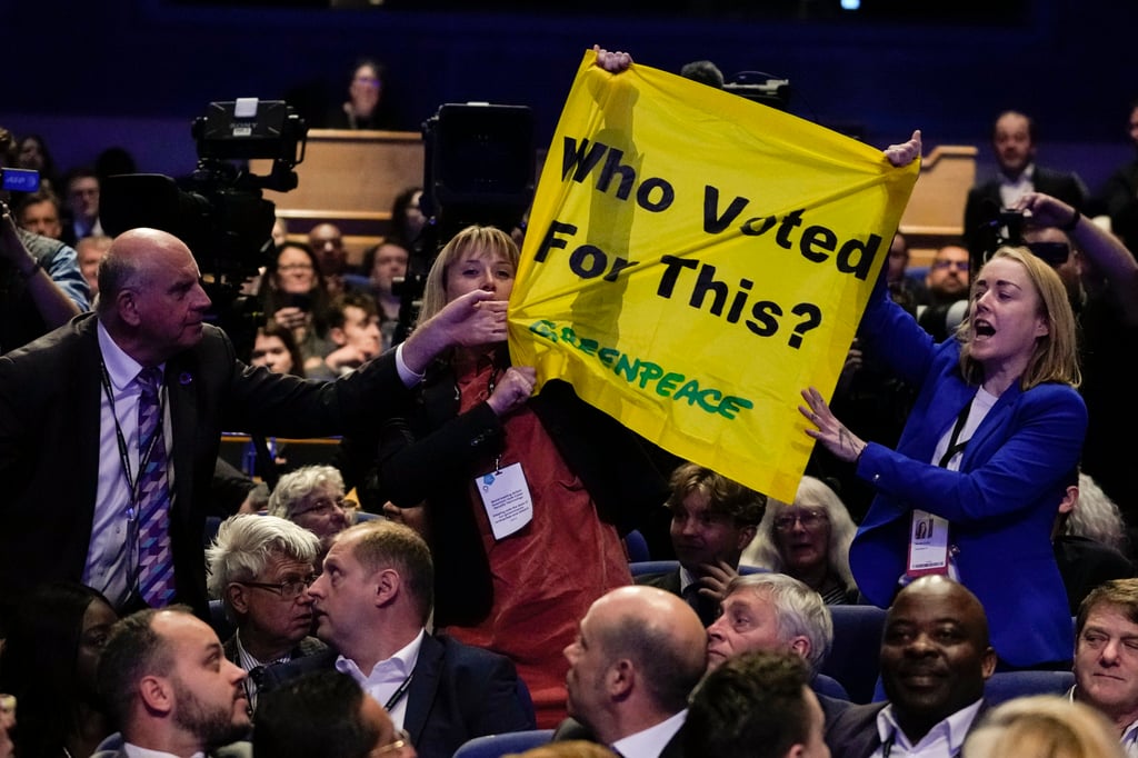 A man pulls down a banner held by two protesters as Britain’s Prime Minister Liz Truss makes a speech at the Conservative Party conference in Birmingham, England earlier this month. Photo: AP A man pulls down a banner held by two protesters as Britain’s Prime Minister Liz Truss makes a speech at the Conservative Party conference in Birmingham, England earlier this month. Photo: AP