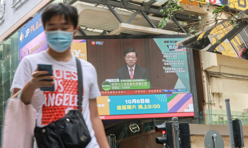 Pedestrian walks under a huge screen showing Hong Kong Chief Executive John Lee delivering his first policy address on Wednesday. Photo: May Tse