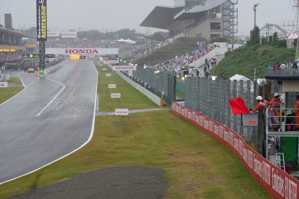 A race marshall waves the red flag as the race is delayed due to heavy rain at Suzuka. Photo: Xinhua A race marshall waves the red flag as the race is delayed due to heavy rain at Suzuka. Photo: Xinhua