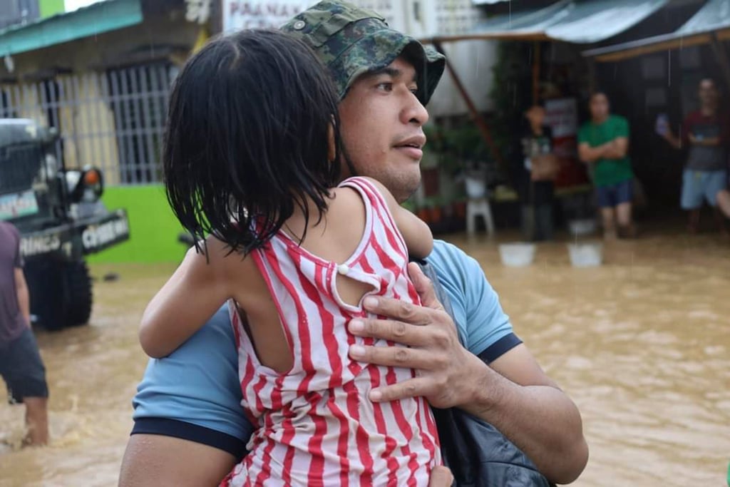 A rescuer carries a child to safer grounds as floods rose in Maguindanao province, southern Philippines. Photo: AP