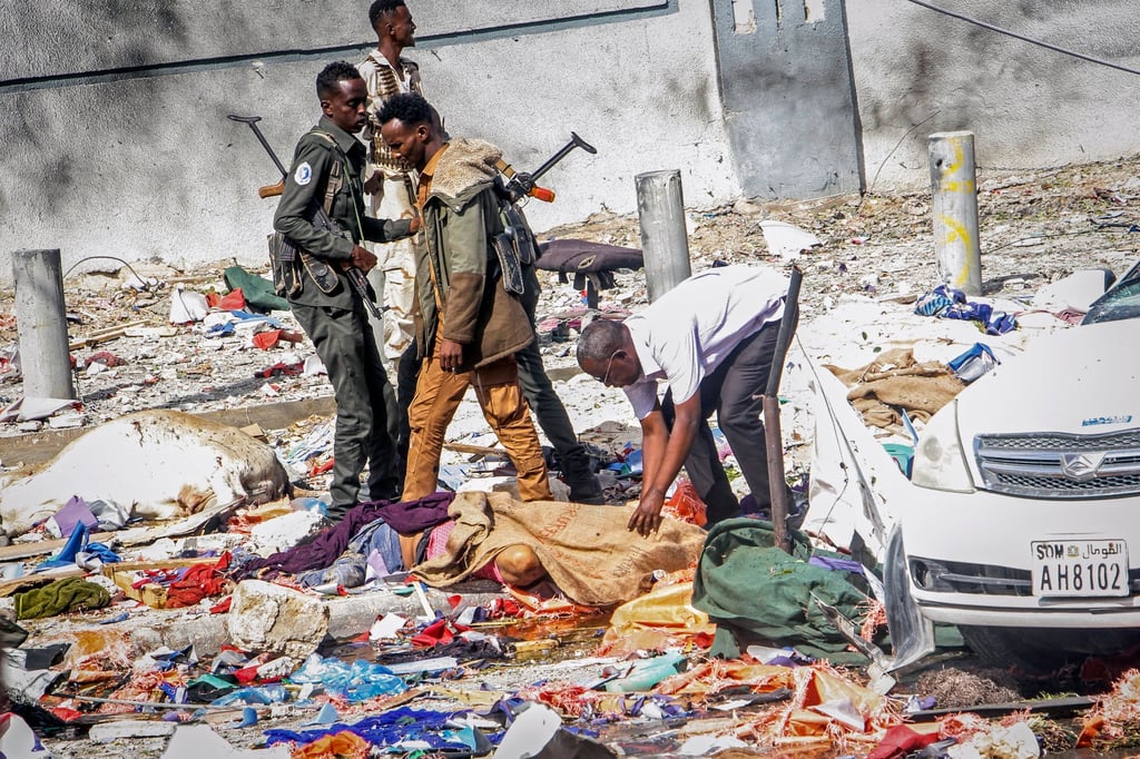 Rescuers and security forces stand by a body at the scene of a double car-bomb attack in Mogadishu, Somalia on Saturday. Photo: AP