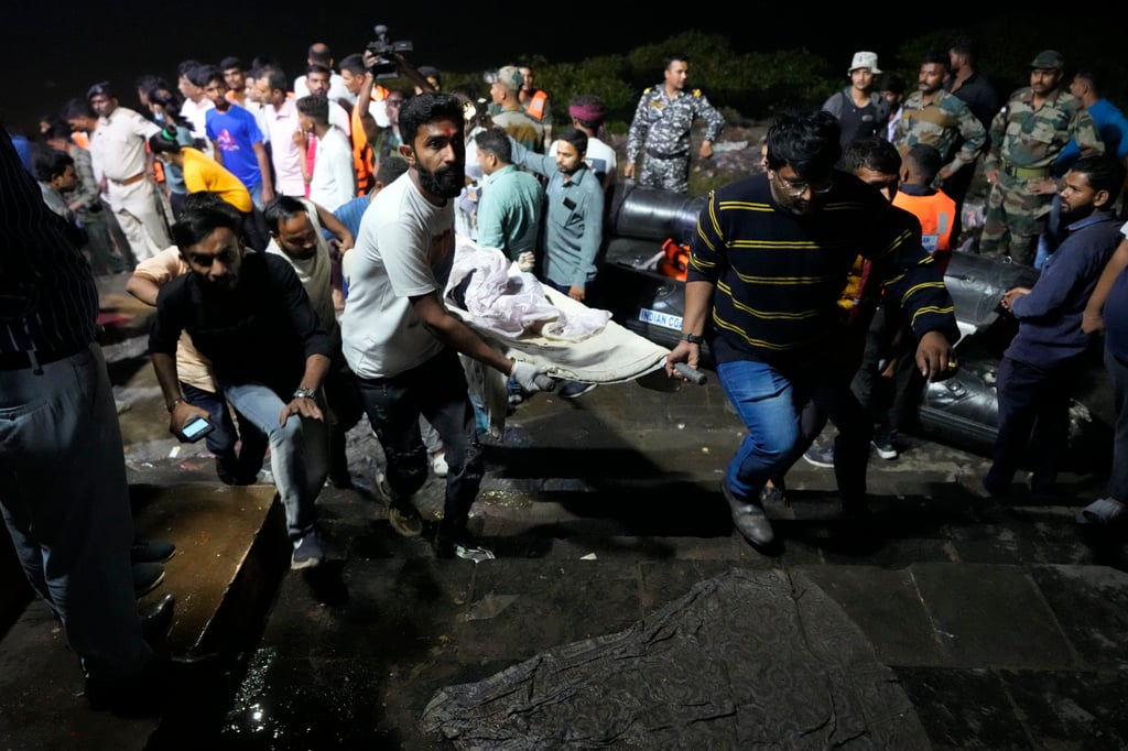 Volunteers and health workers carry a victim of the bridge collapse in Morbi, India’s Gujarat state, early on Monday. Photo: AP