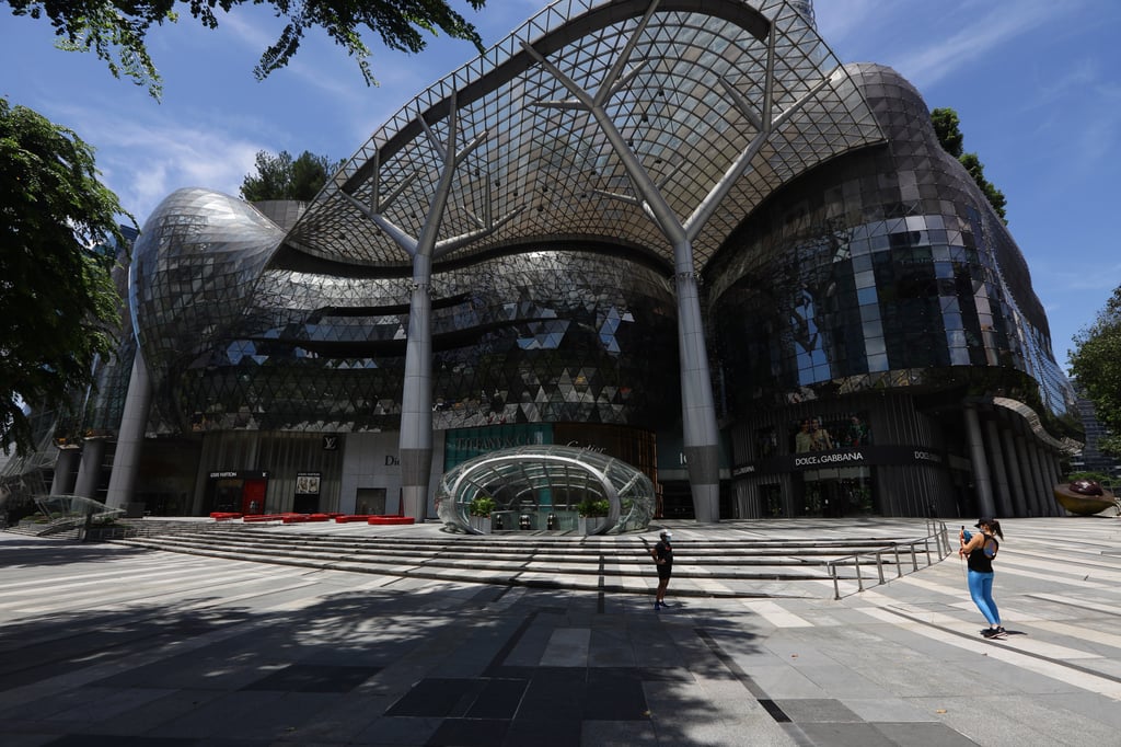 People wearing protective masks take a photo along an almost empty tourist attraction, Orchard Road shopping belt in April 2020, in Singapore, during the pandemic lockdown. Photo: Getty Images