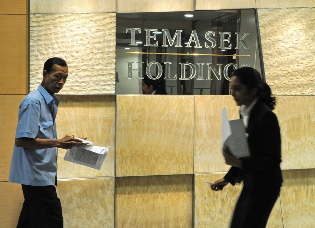 Office workers walk past a signage of Singapore state-owned investment firm Temasek Holdings. Photo: Agence France-Presse